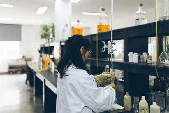 female worker using beakers and equipment on table in factory laboratory